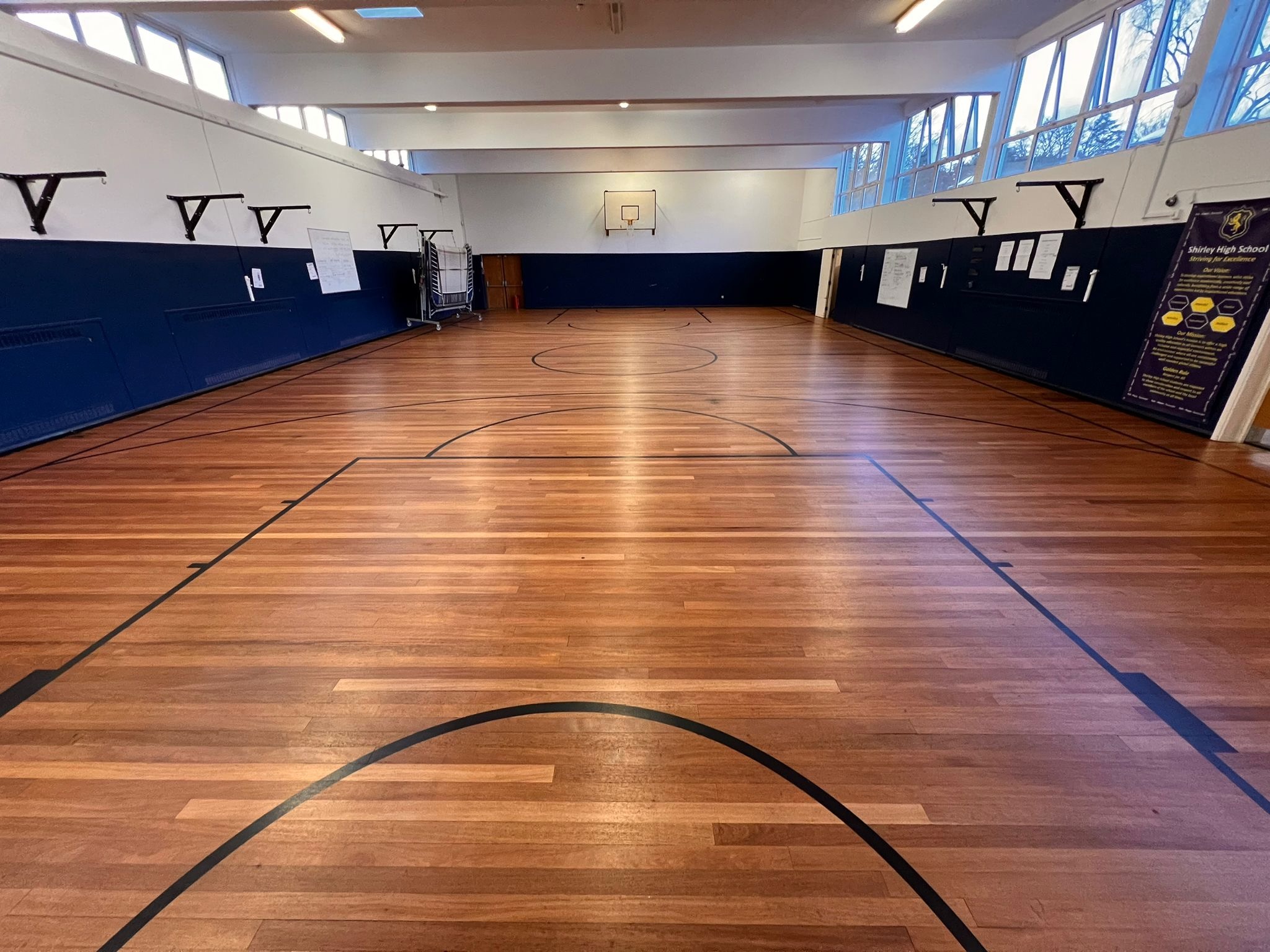 Restored hardwood sports hall floor with basketball court markings at a Croydon secondary school