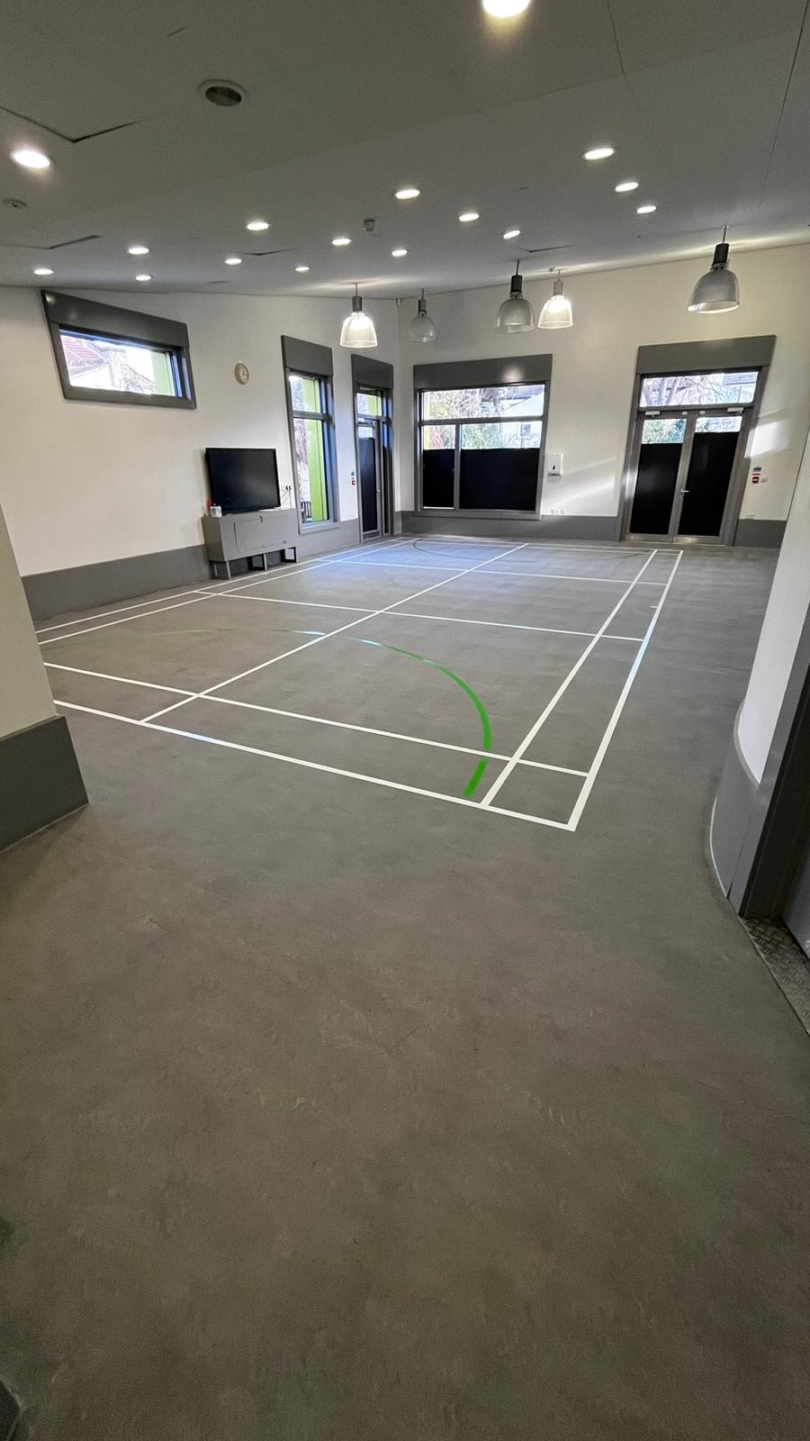 Completed badminton and multi-use court markings on a matt resilient sports hall floor